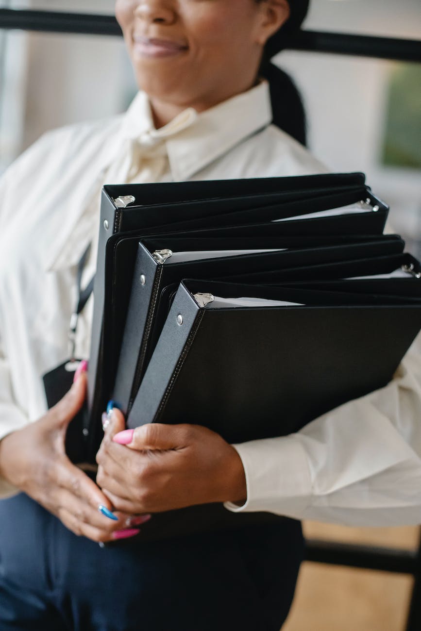 black woman carrying pile of documents in office